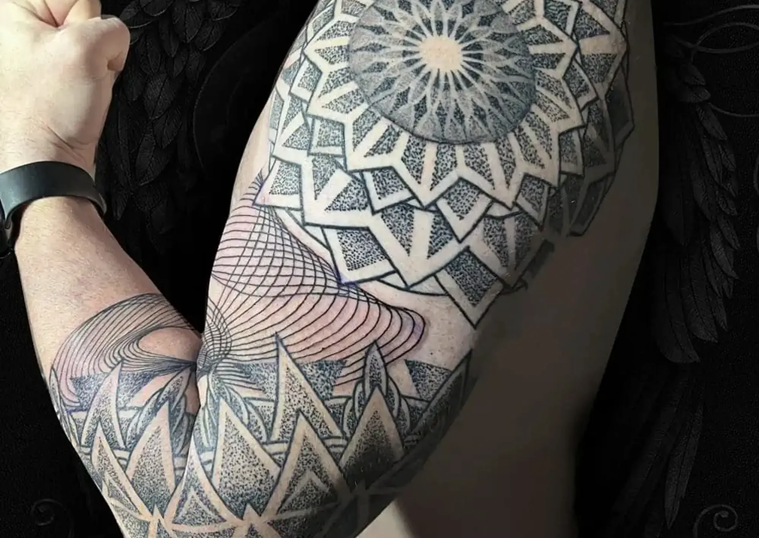 Detailní geometrické tetování s motivem mandaly na paži muže v tetovacím studiu v Praze.