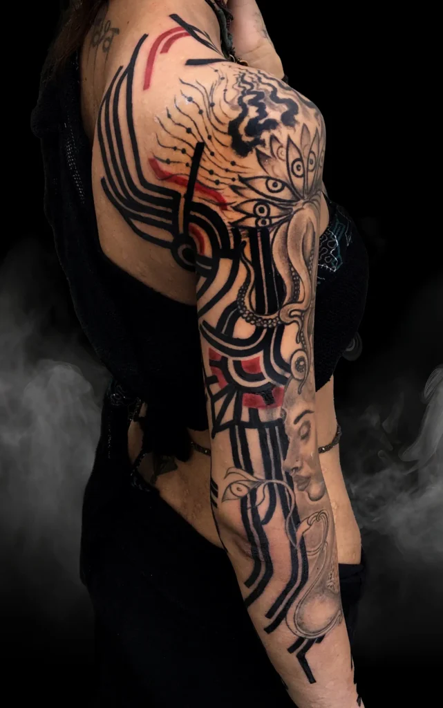 Abstraktní černo-červené tetování s geometrickými liniemi na celé paži od tatéra OMKAR ze studia Magic Tattoo v Praze.