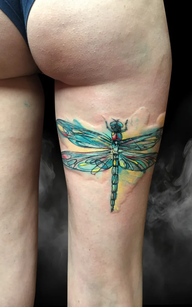 Barevné akvarelové tetování vážky na stehně ze studia Magic Tattoo.